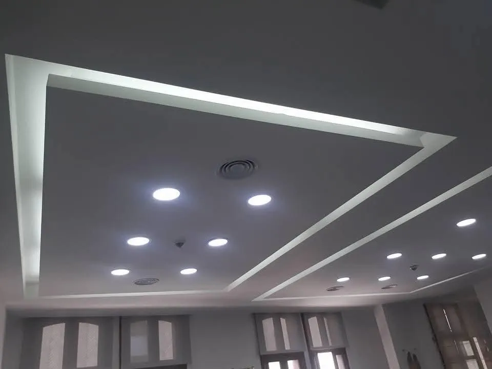Een verlaagd plafond met een lichtkoof in twee lagen en inbouwspots