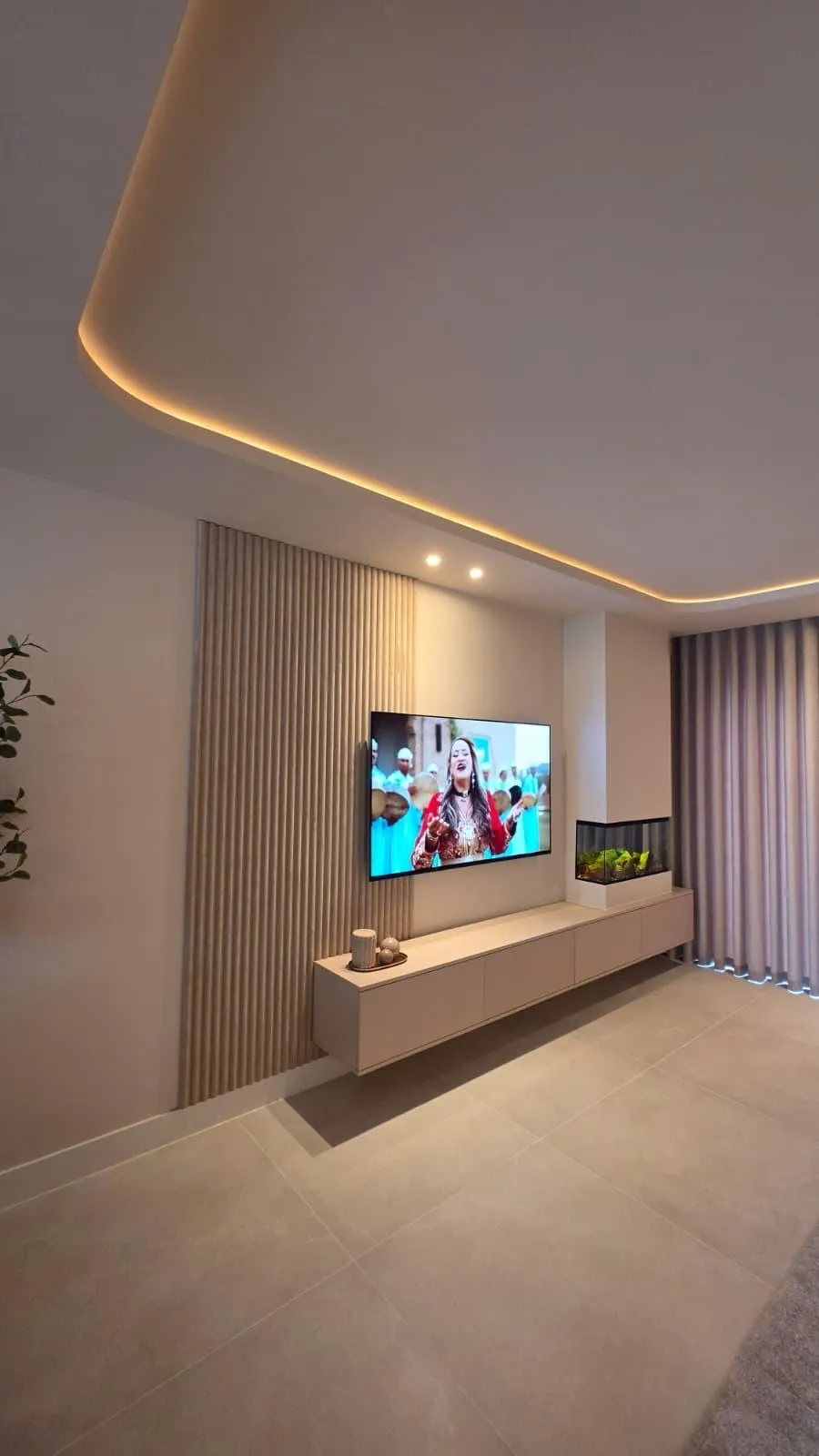 Een tv-wand met een verlichte koof erboven en een zwevend meubel eronder